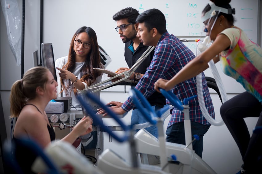 Students in a kinesiology lab monitoring someone on a bike