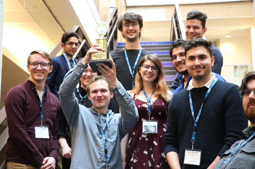 Students on the stairs with one holding a trophy