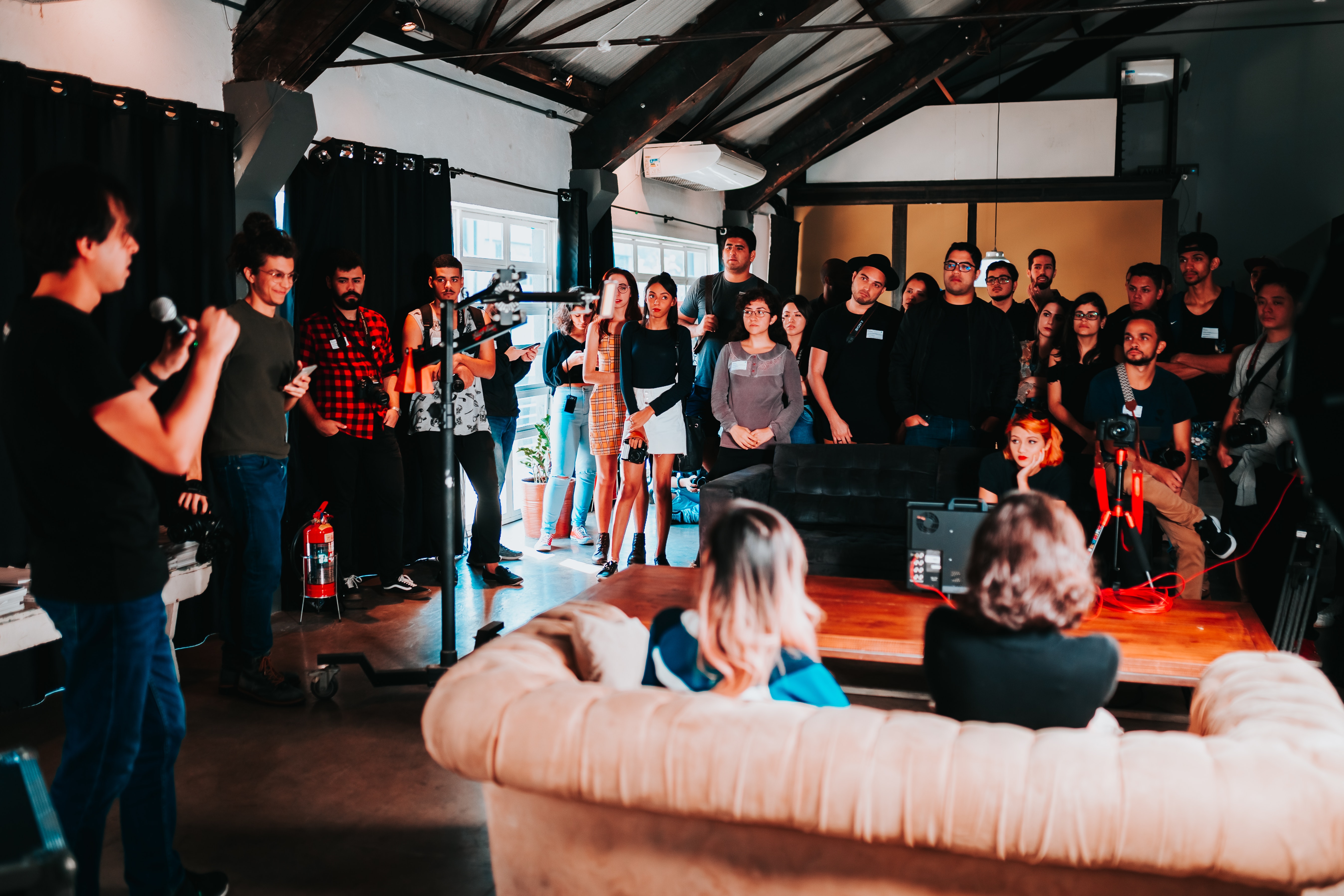 group of people gather in a room listening to a speaker