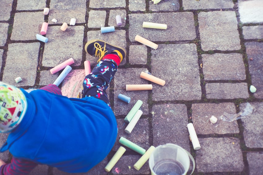 a child plays with sidewalk chalk