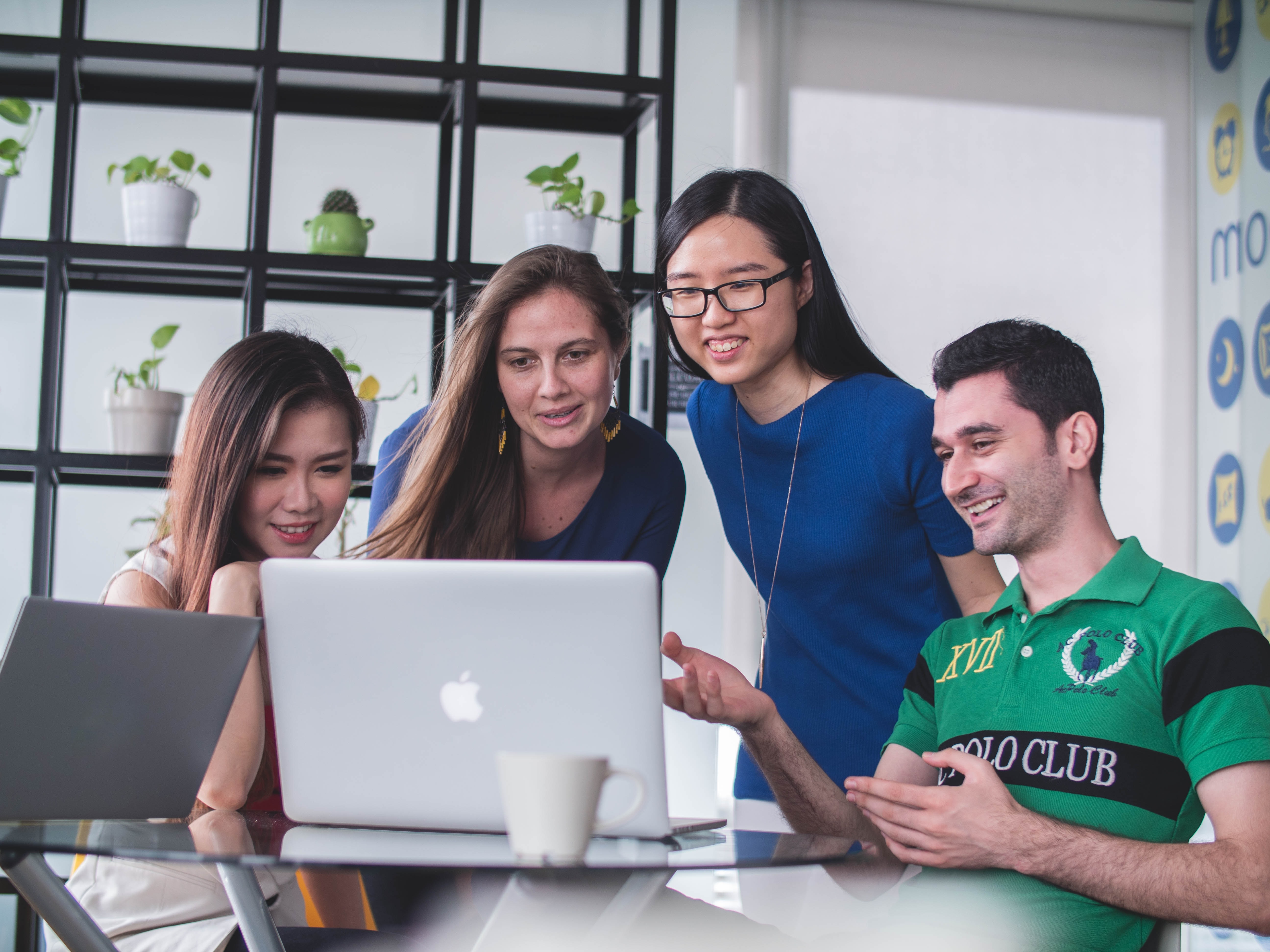 group of people gather in front of a laptop