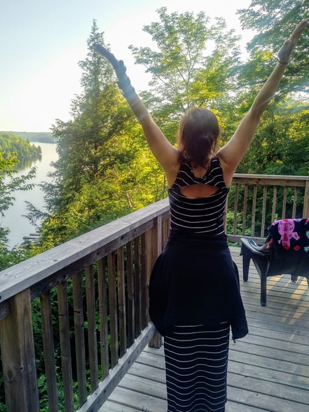 Dr. Diana Petrarca, with her arms open over her head, in celebration of being in the outdoors. 