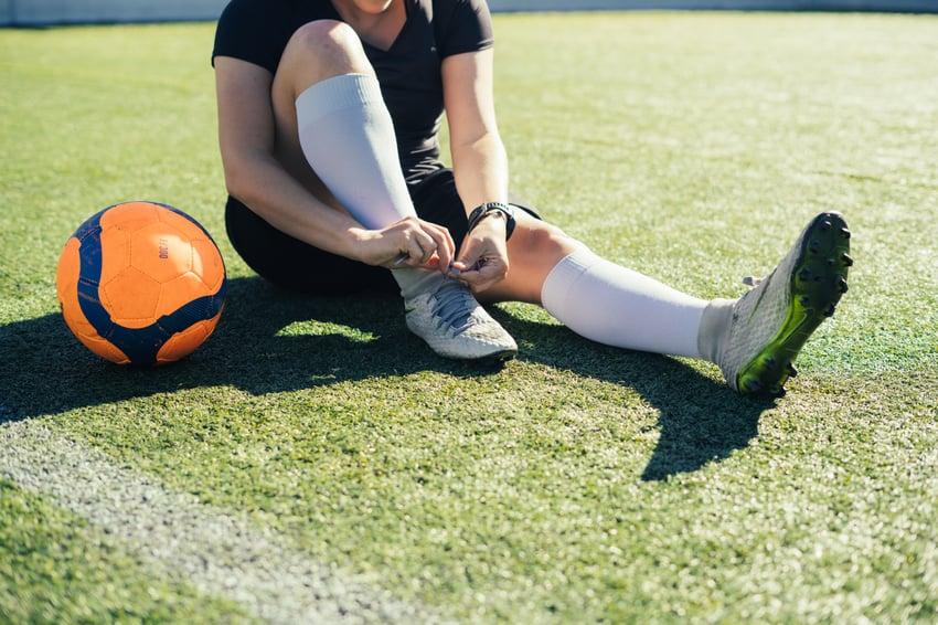 Person tying shoelaces on a soccer field