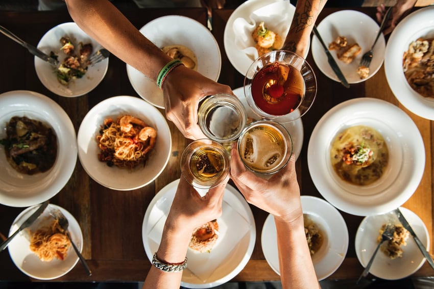 Friends cheers over plates full of food