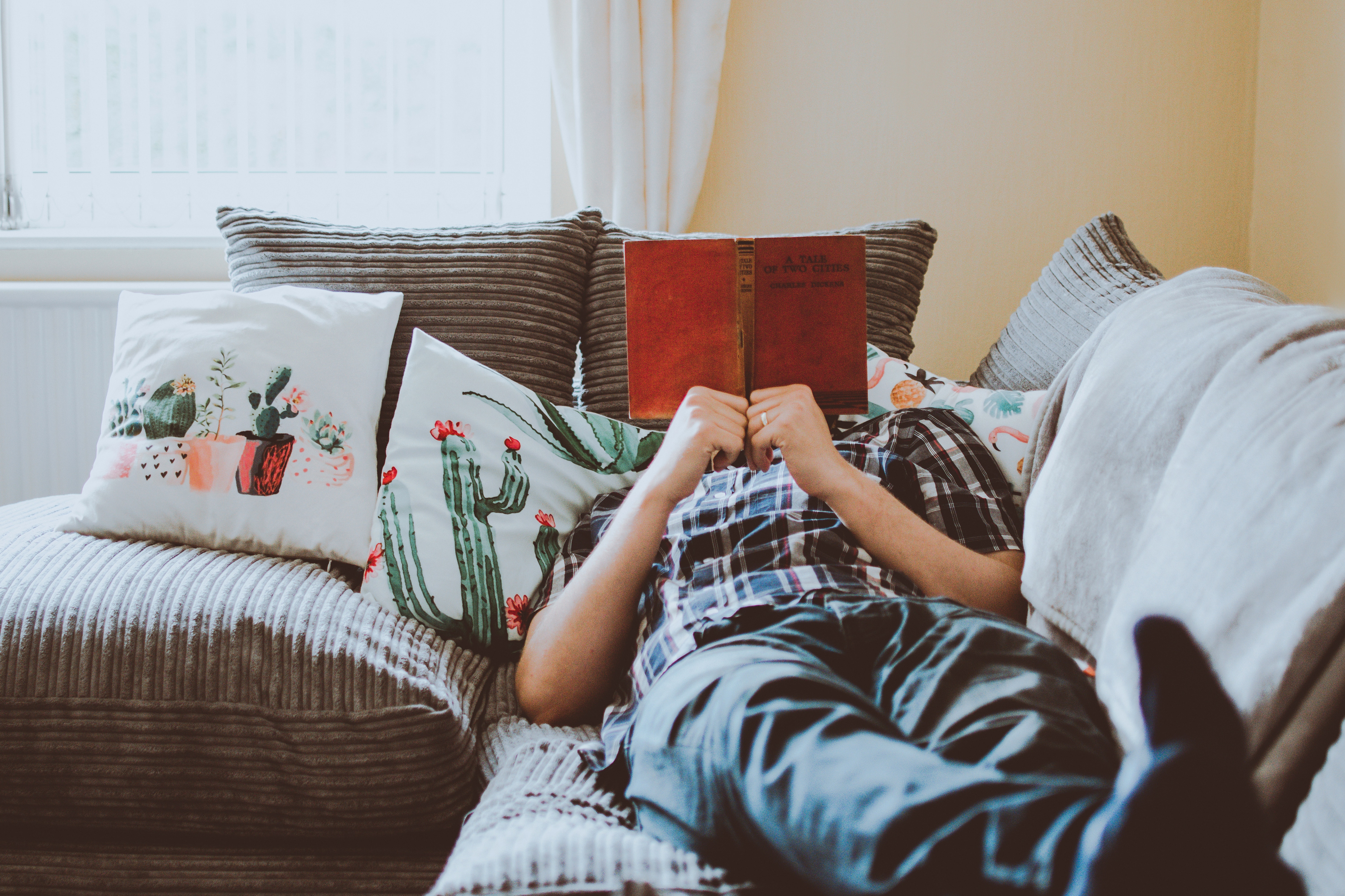 someone laying on a couch reading a book