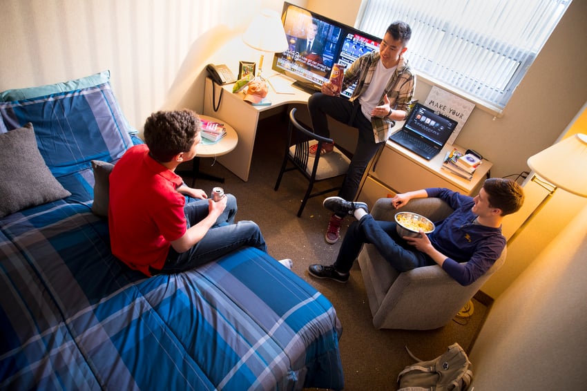 Three people hanging out in a dorm room