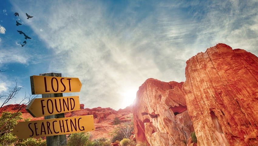 a sign that says lost, found, searching in a valley of red rocks