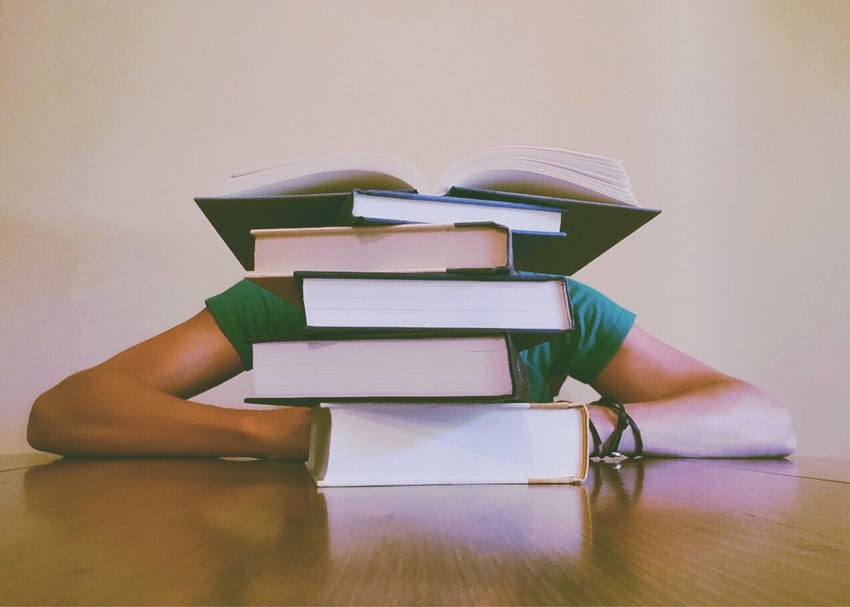 Person hidden behind a stack of books