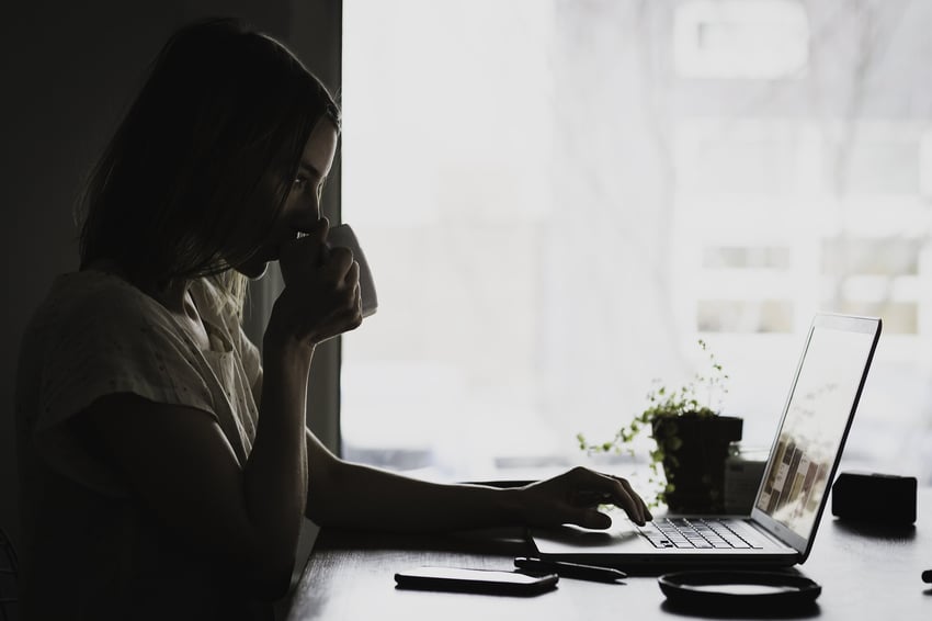 Woman drinking tea while on her laptop