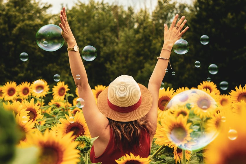 Woman standing in sunflower field with bubbles