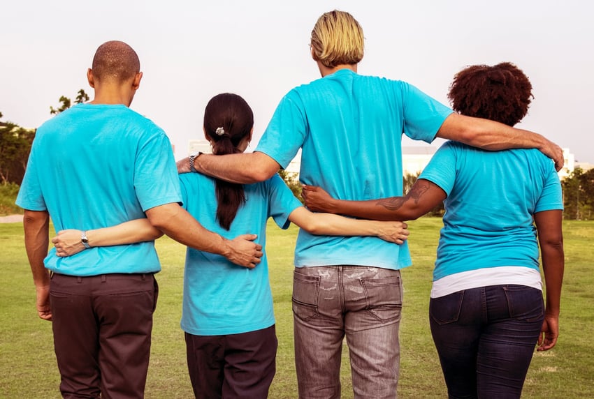 Four people with their backs to the camera and their arms around one another
