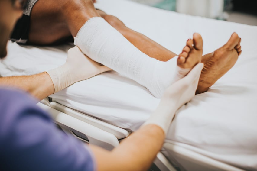 Nurse assisting man with bandaged leg