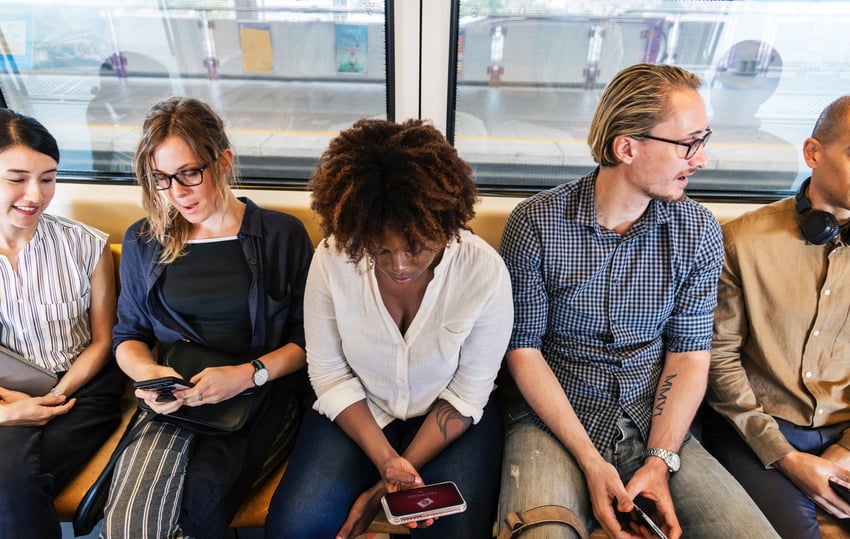 Woman on train looking at phone beside other passengers