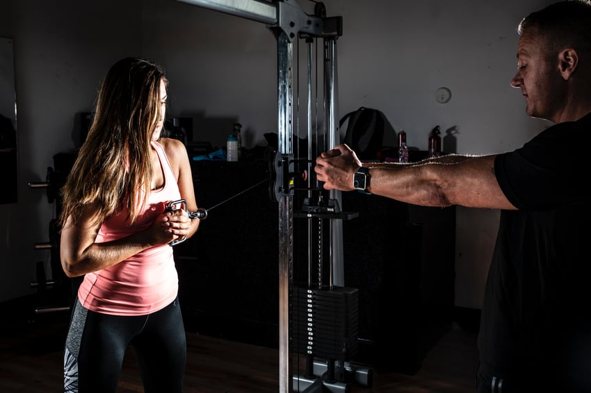 trainer helping girl with fitness machine