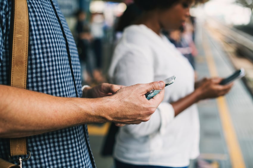 Man looking at phone at train station