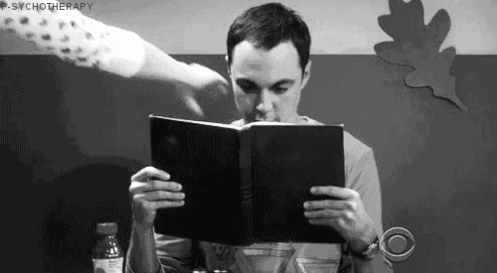 gif of Sheldon reading a comic hidden behind a book 