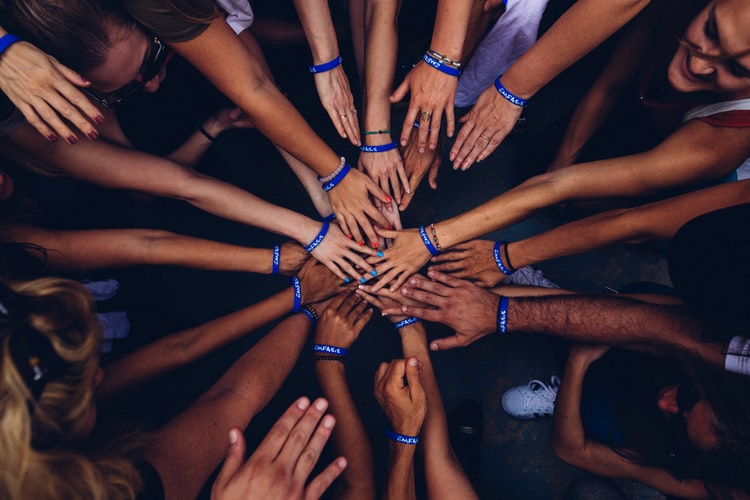 group of people putting hands in a pile