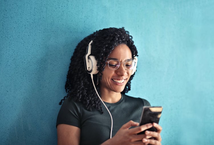 Woman wearing headphones and smiling at phone