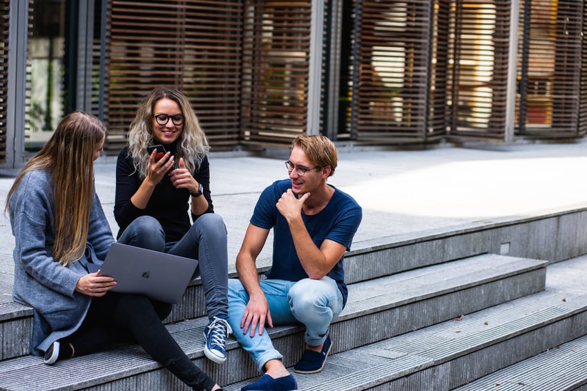 three students sitting on steps