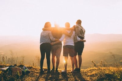 four people embracing while watching the sun set