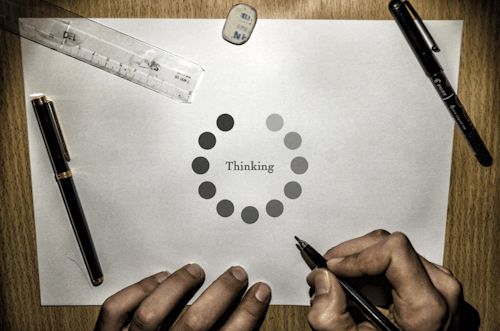 Piece of paper with the word thinking circled by loading dots
